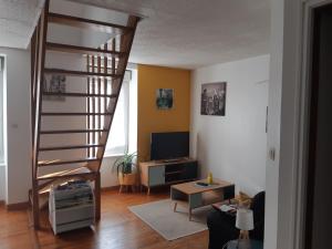 a living room with a spiral staircase and a television at L'escapade Guingampaise in Guingamp