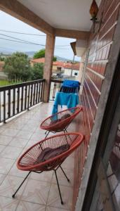 two red chairs on a balcony with a table at Meira House in Belinho