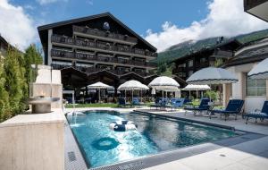 a hotel with a swimming pool in front of a building at Mirabeau Alpine in Zermatt
