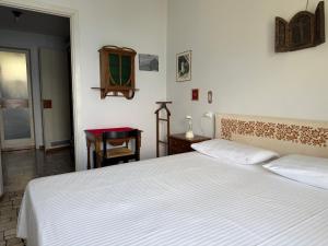 a bedroom with a large white bed and a table at Villa 64 in Fiumelatte +5 photos