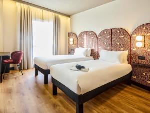 a hotel room with two beds and a chair at Ibis Styles Madrid Centro Maravillas in Madrid
