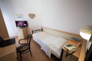 a small room with a bed and a desk with a television at Hotel Madison - Cattolica in Cattolica