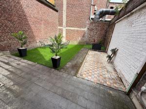 a courtyard with two potted plants and a brick building at le cocon valenciennes gare in Valenciennes