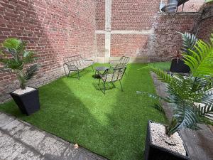 a patio with chairs and plants and a brick wall at le cocon valenciennes gare in Valenciennes