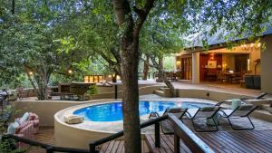 an outdoor pool with chairs and a tree at Shimungwe Lodge, Thornybush Game Reserve in Hoedspruit +106 photos