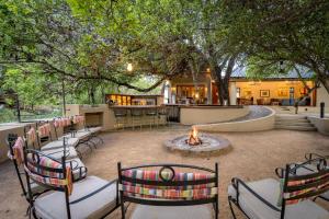 a patio with chairs and a fire pit and a bar at Shimungwe Lodge, Thornybush Game Reserve in Hoedspruit