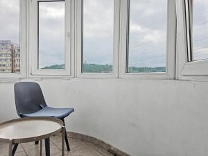 a chair and a table in a room with windows at Konstanzer12 - Free Parking Apt - AC in Iaşi