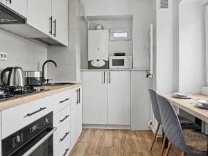 a kitchen with white cabinets and a table with chairs at Konstanzer12 - Free Parking Apt - AC in Iaşi