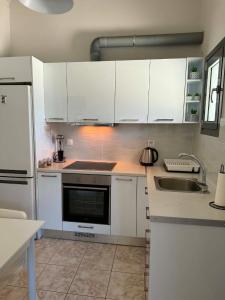 a kitchen with white cabinets and a sink at George's place in Plytra +17 photos