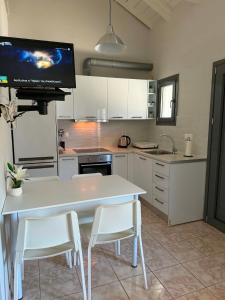 a kitchen with a white table and chairs and a tv at George's place in Plytra