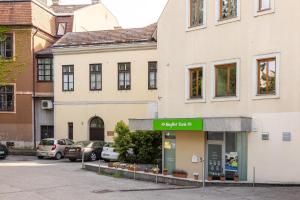a building with a green sign in a parking lot at Szent Margit Apartman in Veszprém
