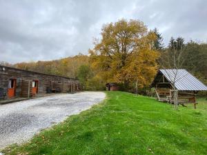 a barn and a grass field next to a gravel road at Forges de Pernelle in Couvin