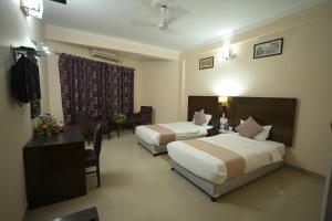 a hotel room with two beds and a table and chairs at Hotel Sujata in Bodh Gaya +40 photos
