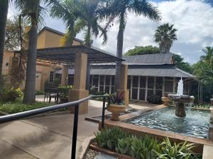 a fountain in front of a building with palm trees at Old Mine Guesthouse in Musina