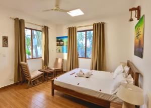 a bedroom with a bed and chairs and windows at Aurora Nungwi in Nungwi