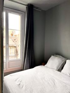 a bedroom with a white bed and a window at Charmant 2 pièces - centre historique - Vieux Mans in Le Mans