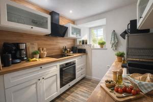 a kitchen with white cabinets and a wooden counter top at Aux 4 Cornes - Chambres d'hôtes et Gite in Longeves