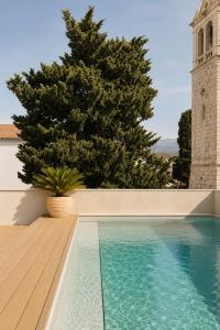a swimming pool with a tree and a clock tower at Hotel Kali in Kali