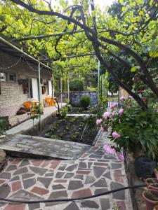 a garden with pink flowers and a stone walkway at BARBIMARIA in Khertʼvisi