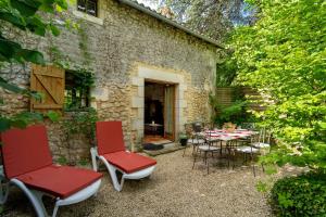 a patio with red chairs and a table in front of a building at Maison Les Rocailles in Saint-Martin-des-Combes