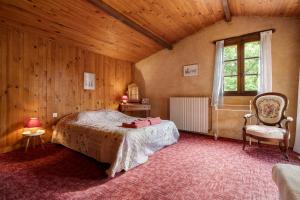 a bedroom with a bed and a chair and a window at Maison Les Rocailles in Saint-Martin-des-Combes