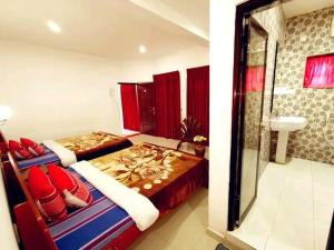 a bedroom with two beds and a bathroom with a sink at Breeze Mahagedara in Nuwara Eliya