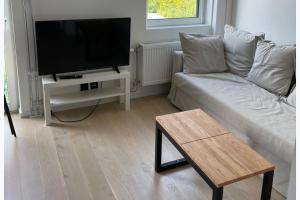 a living room with a white couch and a flat screen tv at Studio Sleeps 2 Sollentuna centre in Sollentuna