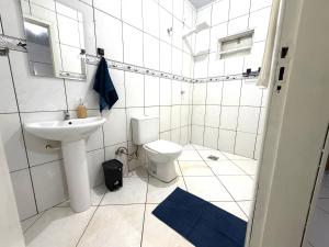 a white bathroom with a sink and a toilet at Suíte premium Ar , WI-FI e TV SMART in Rondonópolis