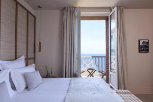 a bedroom with a large white bed and a balcony at Les Bassans - Fontenille Collection in Perros-Guirec