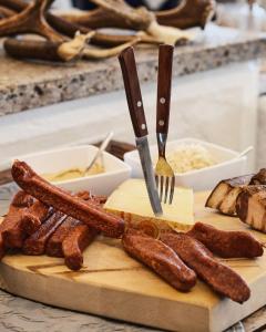 a cutting board with sausages and a knife and fork at Genuss - und Vitalhotel Moisl in Abtenau +65 photos
