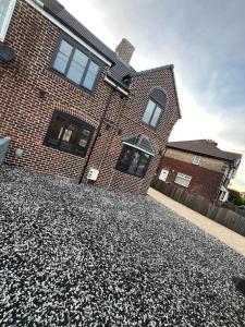 a brick house with a gravel driveway in front of it at Droversdale Delux hottub and pool table in Bircotes