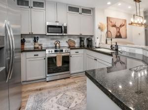 a kitchen with white cabinets and stainless steel appliances at Highlands Slopeside in Beaver Creek