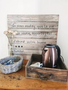 a wooden box with a tea kettle and a basket on a table at Chambre d'hôtes charme Le Trèfle près du Futuroscope Petit-déjeuner in Bonneuil-Matours