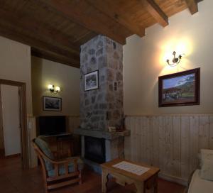 sala de estar con chimenea de piedra y TV en Casa Rural Valdeascas, en Navarredonda de Gredos