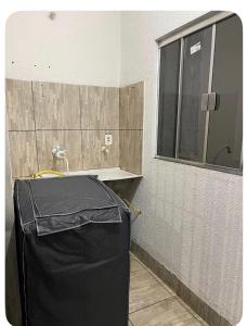 a bathroom with a black trash can and a window at Apartamento próximo ao centro in Primavera do Leste +8 photos