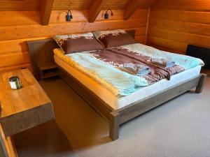 a bed in a wooden room with a table at Chalupa Nicol in Vítějeves