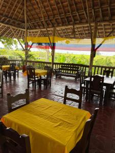 a table and chairs in a restaurant with yellow table cloth at finca hotel palmas frente a panaca in Quimbaya