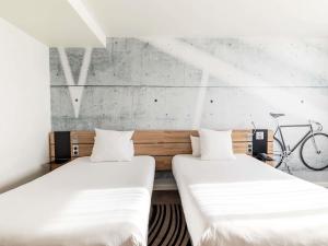 two beds in a room with a bike on the wall at Novotel Kraków City West in Krakow