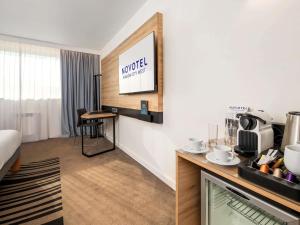 a hotel room with a desk and a tv at Novotel Kraków City West in Krakow +83 photos