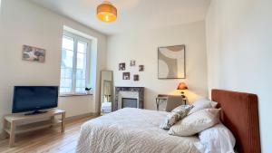 a bedroom with a bed with a television and a fireplace at Le Quai Granvillais in Granville +2 photos