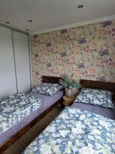 two beds in a room with floral wallpaper at Apartament dla 7 osób in Głogów +1 photo