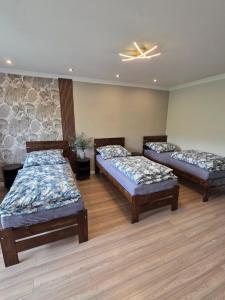 three beds in a room with wooden floors at Apartament dla 7 osób in Głogów