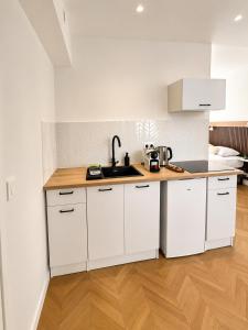 a white kitchen with white cabinets and a sink at Le Thuillat Limoges in Limoges