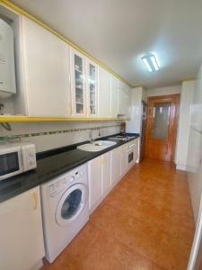 a kitchen with white cabinets and a washer and dryer at Terra marina in Grao de Castellón