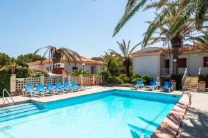 a swimming pool with chairs and a house at Las Belisas in Arenal d'en Castell