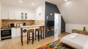 a kitchen with white cabinets and a bed in a room at Luna Apartman in Eger