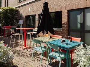 a patio with tables and chairs and an umbrella at ibis Brussels Waterloo in Waterloo +83 photos