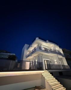 a white building with stairs in front of it at night at Hotel Mihasi in Ksamil