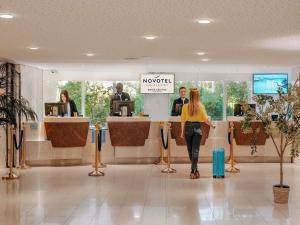 a woman walking through a hotel lobby with her luggage at Novotel Paris Centre Tour Eiffel in Paris