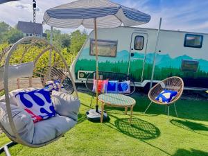 a group of chairs and an umbrella and an rv at Boho luxury caravan in Kisapáti